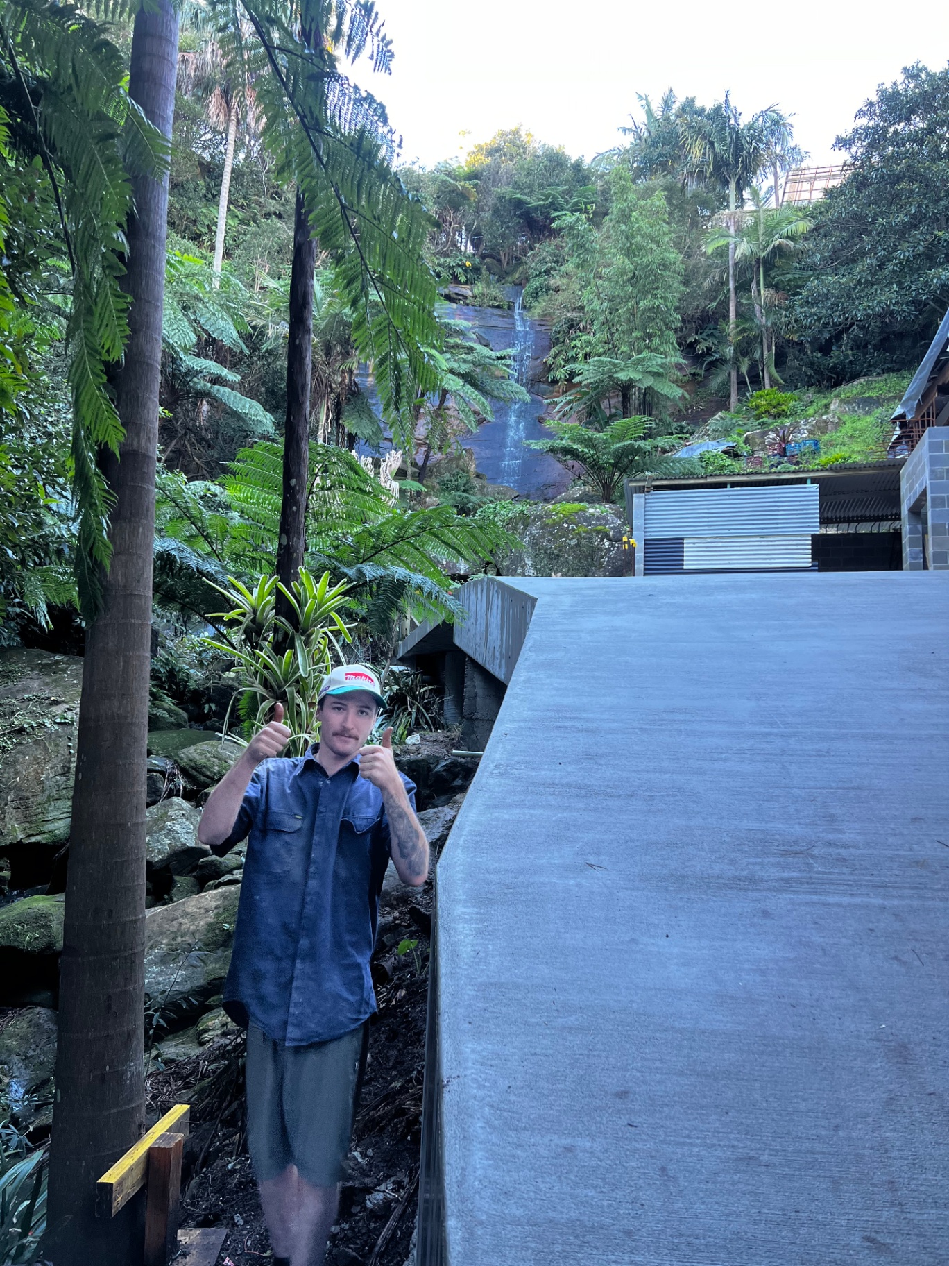 Completed concrete driveway slab on a bushland property with waterfall backdrop